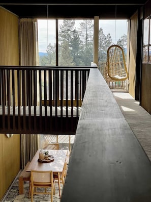 Un long banc en bois offrant une vue sur les arbres à travers de grandes fenêtres.