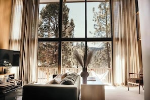 Un salon avec une grande fenêtre, un canapé, un téléviseur et un fauteuil.