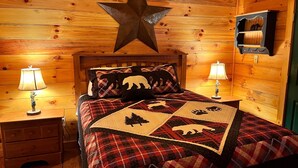 A cozy wooden cabin bedroom with a star decoration, plaid bedding, and two bedside lamps.