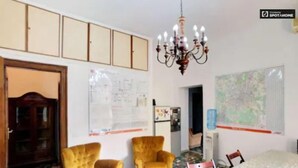 Una habitación con piso estampado, dos sillones amarillos, una araña de cristal, una mesa de comedor y un amplio ventanal con un mapa.