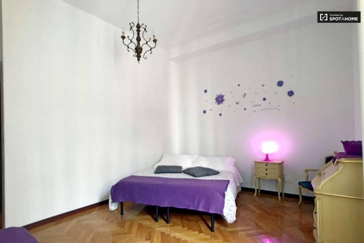 A bedroom with a bed, a dresser, a nightstand, and a chandelier.