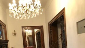 Una sala de estar con sofá, una araña, una mesa de comedor con sillas y suelo estampado.