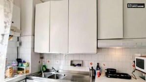 Una cocina con armarios blancos, lavadora, microondas y un lavabo.