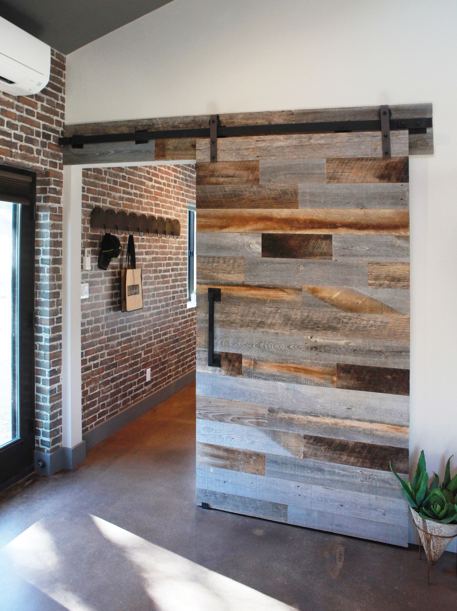 A hallway with a brick wall, a wooden slat wall, and a plant.