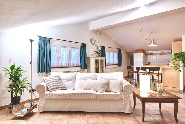 A living room with a white sofa, a small table, and a potted plant. - Lovely Apartment - 5 minutes near the Beach (Forte dei Marmi)