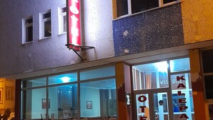 A hotel with a prominent red sign, large windows, and a visible entrance.