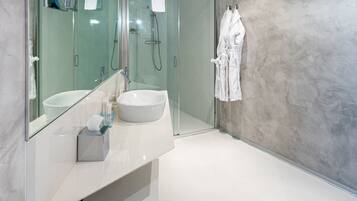 Un bany modern amb un mirall gran, un lavabo blanc i una dutxa amb envàs de vidre.