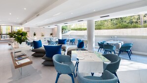 A modern restaurant with a spacious layout, featuring blue chairs and tables, a clear glass partition, and a view of greenery outside. - Carrick Hotel Camogli Portofino Coast (Camogli)