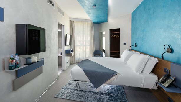A modern hotel room with a large bed, a flat-screen TV, a bedside phone, and a wardrobe. - Carrick Hotel Camogli Portofino Coast (Camogli)