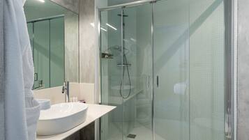 A modern bathroom with a glass-enclosed shower, a large mirror, and a white sink.