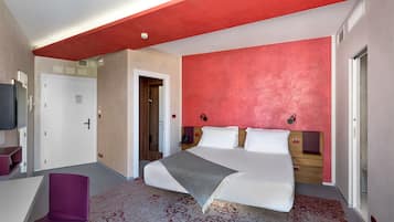 A modern hotel room with a large bed, a desk, and a chair.
