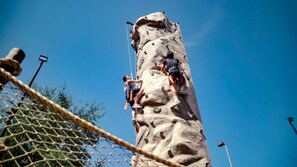 Two individuals climbing a rock wall with safety ropes and a netted safety barrier. - One Bedroom Condo, Calypso Cay Resort (2730239) (Kissimmee)