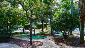 Un jardín bien cuidado con diversos árboles y arbustos, un sendero serpenteante y un pequeño espacio verde.