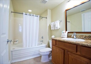 A bathroom with a bathtub, toilet, and vanity with a sink and mirror. - One Bedroom Condo, Calypso Cay Resort (2730239) (Kissimmee)