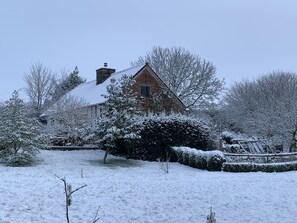A snow-covered house with a brick exterior and a chimney.