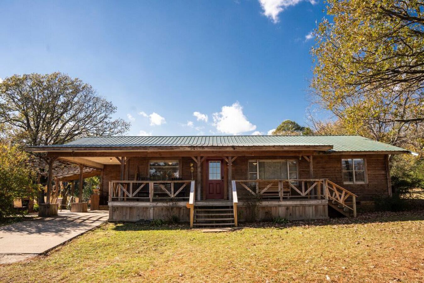 A rustic wooden cabin with a porch and a green metal roof.