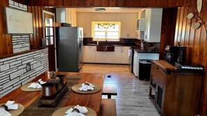 A cozy, wood-paneled room with a dining area, kitchen, and a fireplace.