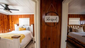 A bedroom with wooden walls, a bed with a yellow pillow, and a 'blessed' sign on the door.