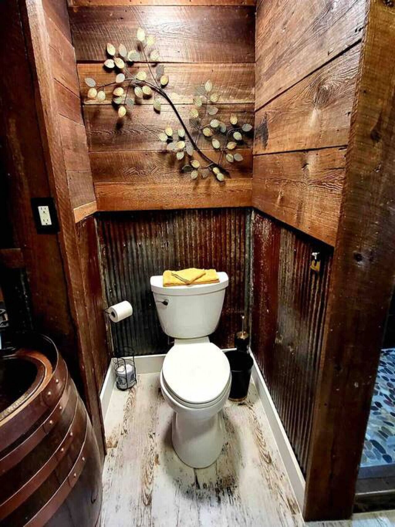 Een badkamer met een houten wand, een wit toilet en een decoratieve tak aan de muur.