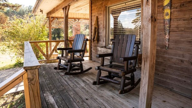 A wooden porch with two rocking chairs and a wooden railing.