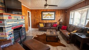 A cozy living room with leather furniture, a fireplace, and a wooden wall.