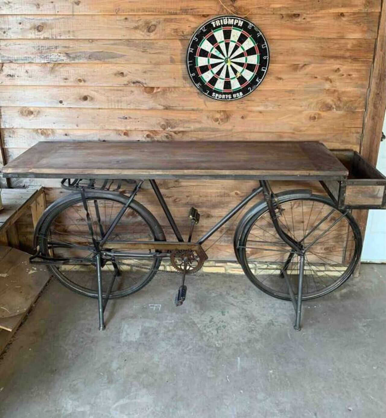A bicycle table with a dartboard mounted on a wooden wall.