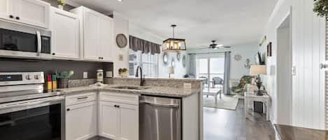 Condo com design assinado, 2 quartos, sacada, vista para a praia | Cozinha privada | Geladeira, micro-ondas, fogão, cooktop