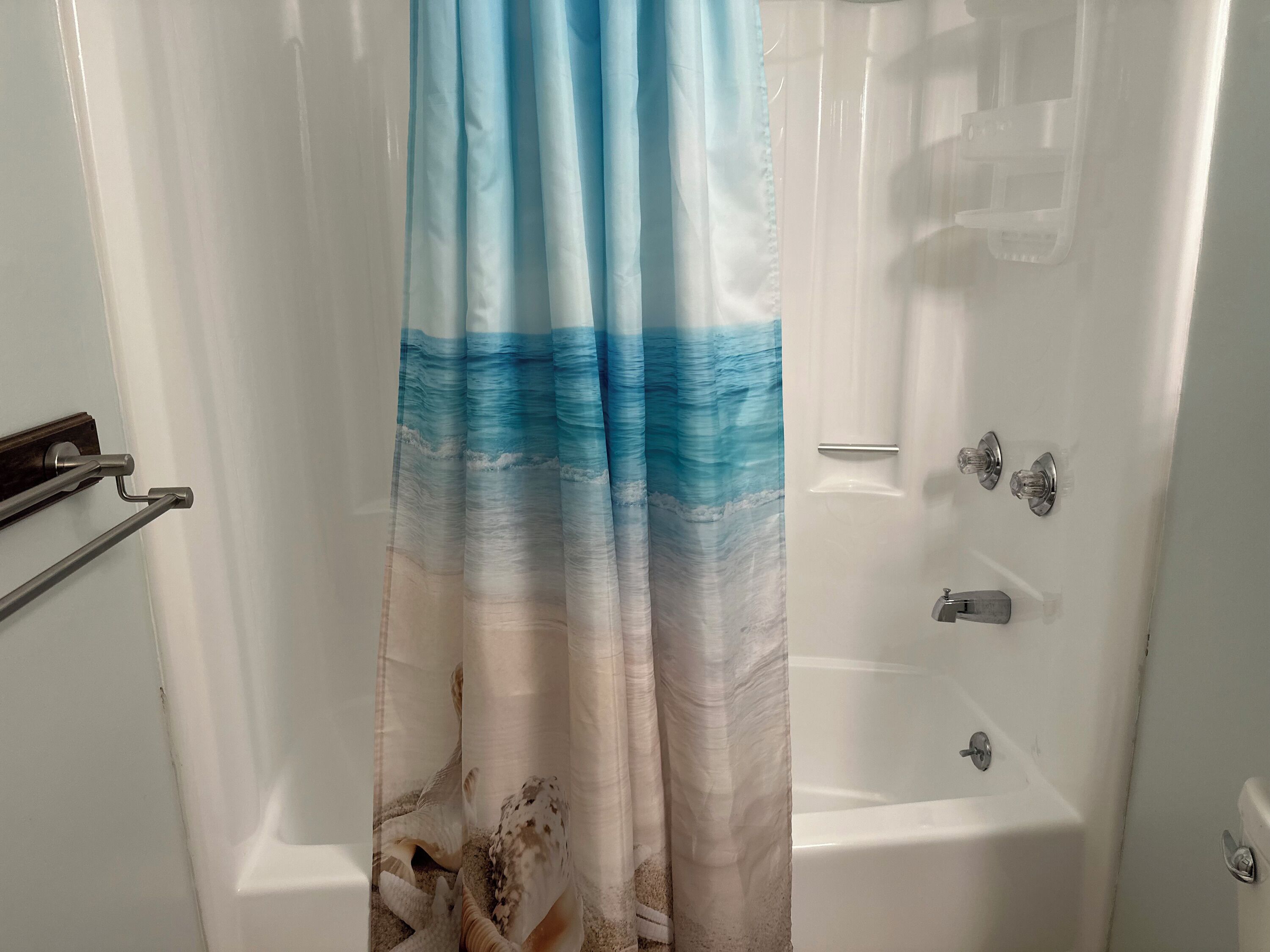 A bathroom with a bathtub, a shower, and a curtain with a wave pattern.