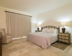 A bedroom with a bed, two bedside tables with lamps, a chair, and a large window with curtains. - Ocean View Condo at Pool-Beach and Golf Resort with Concierge, Maids and Chef - Meal Services (La Paz)