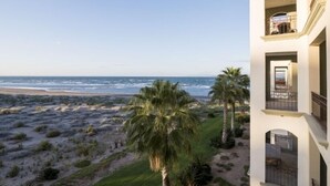 A beachfront property with a view of the ocean, palm trees, and a building with balconies. - Ocean View Condo at Pool-Beach and Golf Resort with Concierge, Maids and Chef - Meal Services (La Paz)