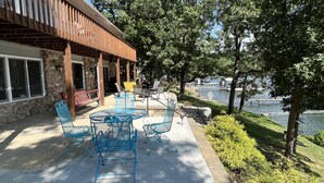 An outdoor patio with blue metal chairs and a table, a wooden pergola, and a stone wall. - PEACEFUL HOME-4 BEDROOMS, 3 KING BEDS, 4 BATHROOMS, EASY PARKING & A BOAT SLIP! (Camdenton)
