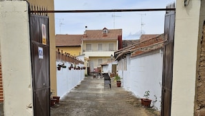 A narrow alleyway leading to a gated entrance with a building in the background. - RURAL ENVIRONMENT, land of fields and vineyards.GORDONCILLO (Gordoncillo)