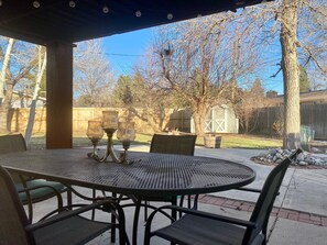 Relax in the serene patio area with a round table and four chairs, surrounded by a wooden fence and leafless trees.