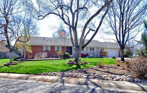 Stunning single-story home with a manicured lawn and a variety of shrubs and small trees.