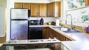 Una cocina moderna con armarios de madera, electrodomésticos de acero inoxidable y un amplio ventanal que proporciona luz natural.