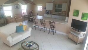 A living room with a sofa, coffee table, and dining area with chairs. - Port Charlotte House on the Canal   (Port Charlotte)