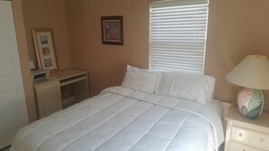 Une chambre à coucher avec un lit, un bureau, une lampe et une fenêtre avec des stores.
