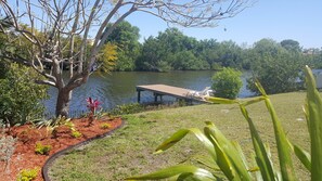 A lakeside garden with a dock, a variety of plants, and a tree. - Port Charlotte House on the Canal   (Port Charlotte)