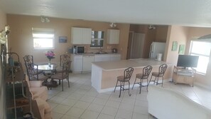 A compact kitchen with a dining area, white cabinets, a small island, and a television. - Port Charlotte House on the Canal   (Port Charlotte)