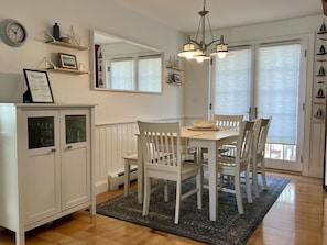 A dining area with a white table, chairs, a chandelier, and a cabinet with glass doors.