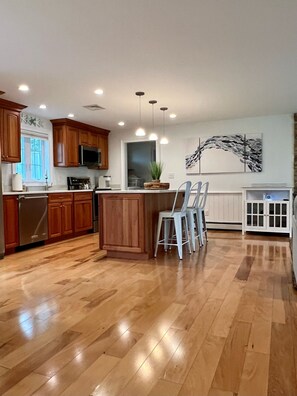 A modern kitchen with wooden cabinets, a central island, and pendant lighting.