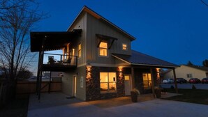 Une maison à deux étages avec un balcon, une façade en pierre et un garage.