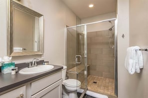 A modern bathroom with a glass-enclosed shower, a white sink, and a large mirror. - Luxury Two Bedroom Condo - Heart of Town Center (Big Sky)