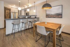 Een moderne keuken met witte kasten, roestvrijstalen apparatuur en een houten kookeiland met barkrukken.