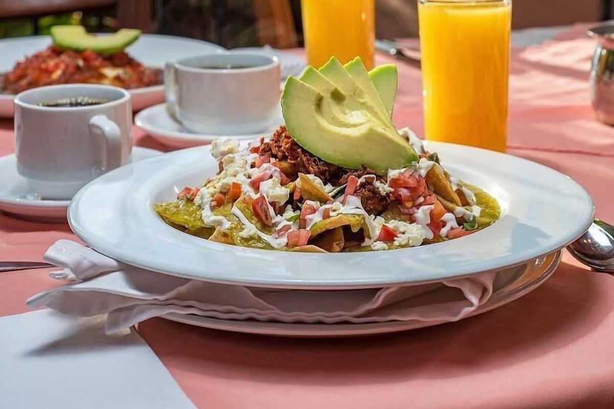 Una mesa dispuesta con un plato de comida, un vaso de jugo de naranja y una taza de café.