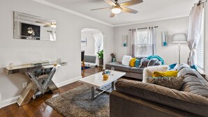 Ein modernes Wohnzimmer mit Deckenventilator, einem weißen Couchtisch, einem braunen Sofa und einem grauen Couch.