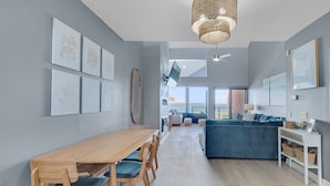 Un espacio habitable moderno con comedor, sofá y vista al mar.