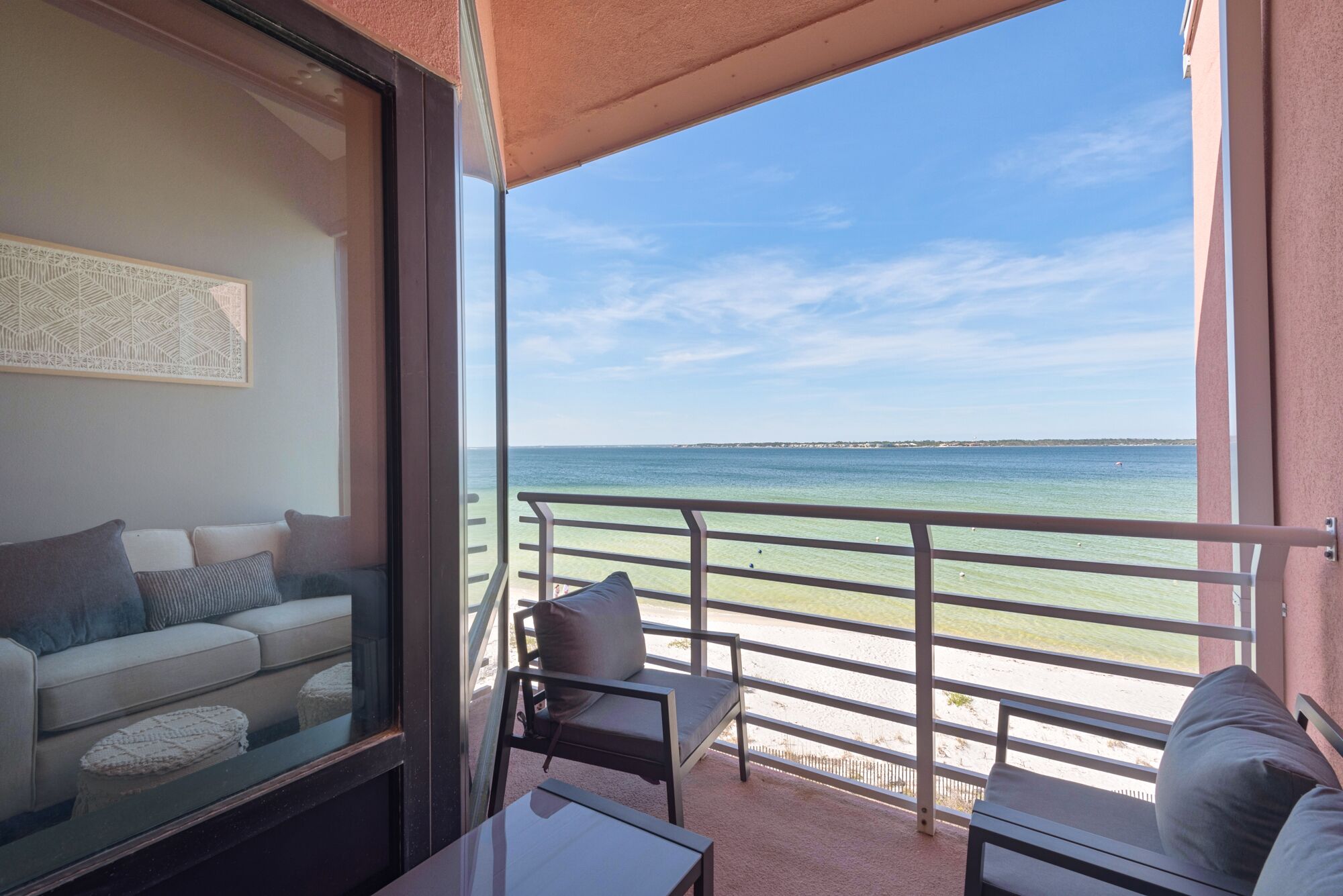 A balcony with a view of the sea, a sofa, and a table.