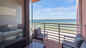 Un balcón con vista al mar, un sofá y una mesa.