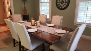 A dining room with a wooden table set for four, surrounded by four upholstered chairs with button details. - Book with an owner not a management company-personalized service! Great reviews (Pawleys Island)
